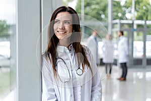 Portrait of young woman doctor with white coat standing in hospital.