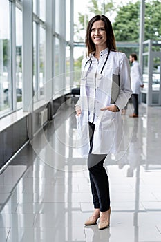 Portrait of young woman doctor with white coat standing in hospital.