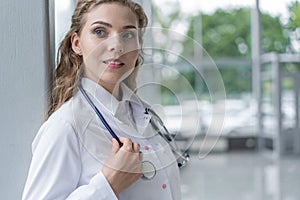 Portrait of young woman doctor with white coat standing in hospital.