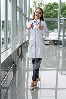 Portrait of young woman doctor with white coat standing in hospital.