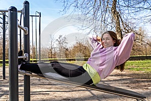 portrait of young woman doing abdominal muscles workout on a bench outdoors