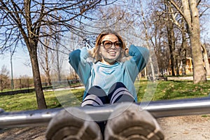 portrait of young woman doing abdominal muscles workout on a bench outdoors