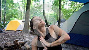 Portrait of young woman doing namaste hands praying pose and looking to the sky while doing yoga in a camping vacation