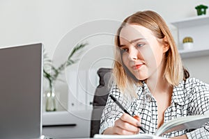 Portrait Young woman doing paper work in office using laptop During working day In office interior. Student girl