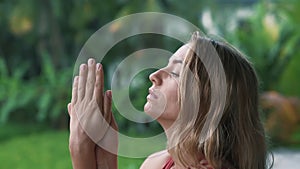 Portrait of young woman doing yoga exercises on balcony, greenery on background