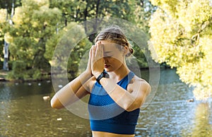 Portrait of a young woman doing yoga in the park near lake for a workout.