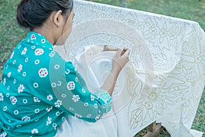 Portrait young woman drawing batik in the garden