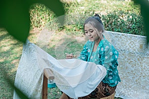 Portrait young woman drawing batik in the garden