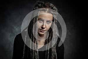 Portrait of a young woman with dreadlocks against dark background