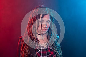 Portrait of young woman with dreadlocks having fun over the dark background