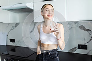 Portrait of a young woman drinking water in the kitchen at home