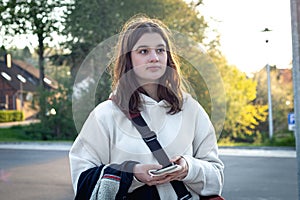 Portrait of a young woman early in the morning at a bus stop.