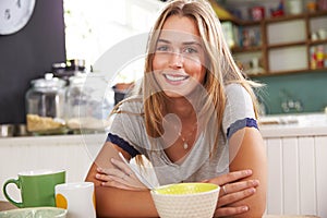 Portrait Of Young Woman Eating Breakfast In Kitchen