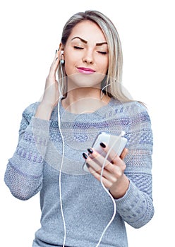 Portrait of young woman enjoying music using headphones, isolated over white