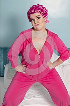 Portrait of young woman exercising with hands on hips standing on bed