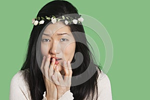 Portrait of a young woman expressing fear and anxiety over green background