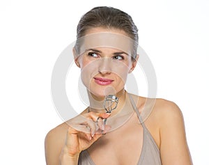 Portrait of young woman with eyelash curler