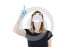 Portrait of young woman with face mask and blue gloves pointing finger up, 2019-nCov.