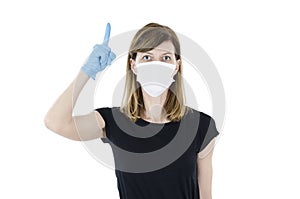 Portrait of young woman with face mask and blue gloves pointing finger up. Covid-19.