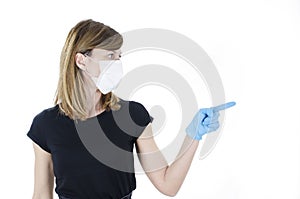 Portrait of young woman with face mask and blue gloves pointing side on copy space,