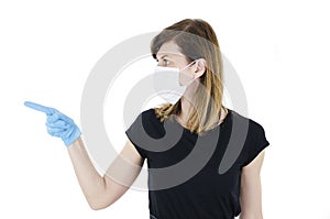 Portrait of young woman with face mask and blue gloves pointing side on copy space,