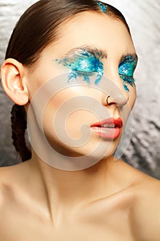 Portrait of young woman with fashion make up with blue eye wearing earring in her nose. Beauty concept.