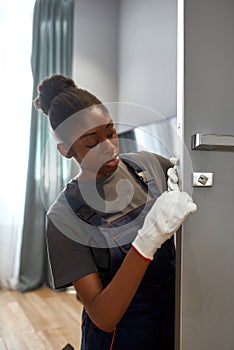 Portrait of young woman fixing door with screwdriver