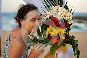 Portrait of young woman with flower bouquet. Wedding decoration at the beach