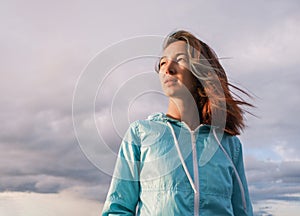 Portrait of a young woman with fluttering hair during the sunset.