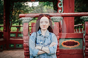 Portrait of young woman with freckles looking into the camera, in Korean style garden