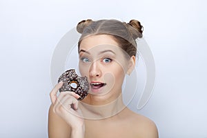 Portrait of a young woman with funny hairstyle and bare shoulders act the ape against white studio background with chocolate donut