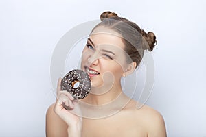 Portrait of a young woman with funny hairstyle and bare shoulders act the ape against white studio background with chocolate donut