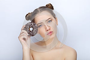 Portrait of a young woman with funny hairstyle and bare shoulders act the ape against white studio background with chocolate donut