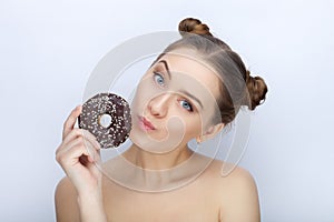 Portrait of a young woman with funny hairstyle and bare shoulders act the ape against white studio background with chocolate donut