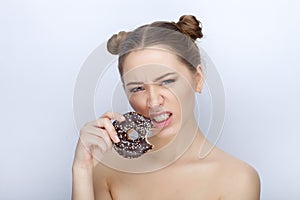 Portrait of a young woman with funny hairstyle and bare shoulders act the ape against white studio background with chocolate donut