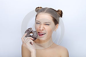 Portrait of a young woman with funny hairstyle and bare shoulders act the ape against white studio background with chocolate donut