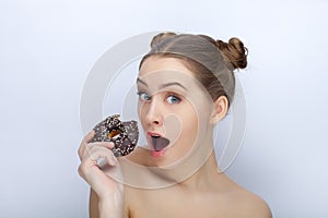 Portrait of a young woman with funny hairstyle and bare shoulders act the ape against white studio background with chocolate donut