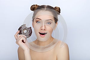 Portrait of a young woman with funny hairstyle and bare shoulders act the ape against white studio background with chocolate donut