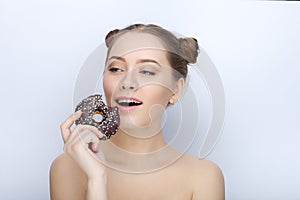 Portrait of a young woman with funny hairstyle and bare shoulders act the ape against white studio background with chocolate donut