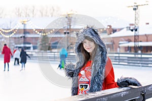 Portrait young woman in fur hat with ears and red sweater, with gloves on ice