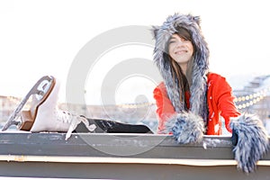 Portrait young woman in fur hat with ears and red sweater, with gloves on ice