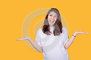 Portrait of a young woman gesturing on a yellow background.