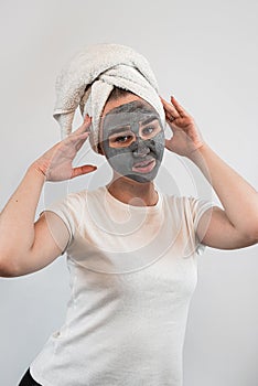 portrait of young woman getting facial care clay or mud mask isolated on white