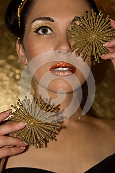 Portrait of young woman with gold makeup and Christmas ornament