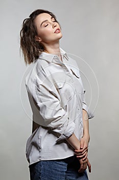 Portrait of young woman on gray background. Female posing in jeans, and milky white corduroy shirt