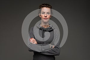 Portrait of young woman in grey hoodie against gloomy background isolated