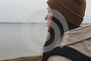 Portrait of young woman in a hat looking over the sea or the ocean, enjoying amazing nature, feeling of freedom