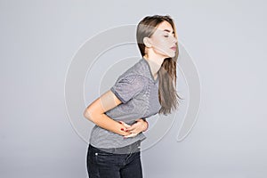 Portrait of young woman having a stomachache, menstruation pain or cramps, isolated on grey background