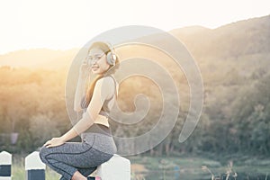 Portrait young woman with headphone listening to music after hard workout. Smiling attractive girl relaxing and resting after goo