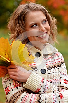 Portrait of young woman holding autumn leaves